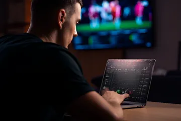 A man celebrating a winning moment on his laptop while gaming symbols float around him, capturing the excitement of 599JILI games.